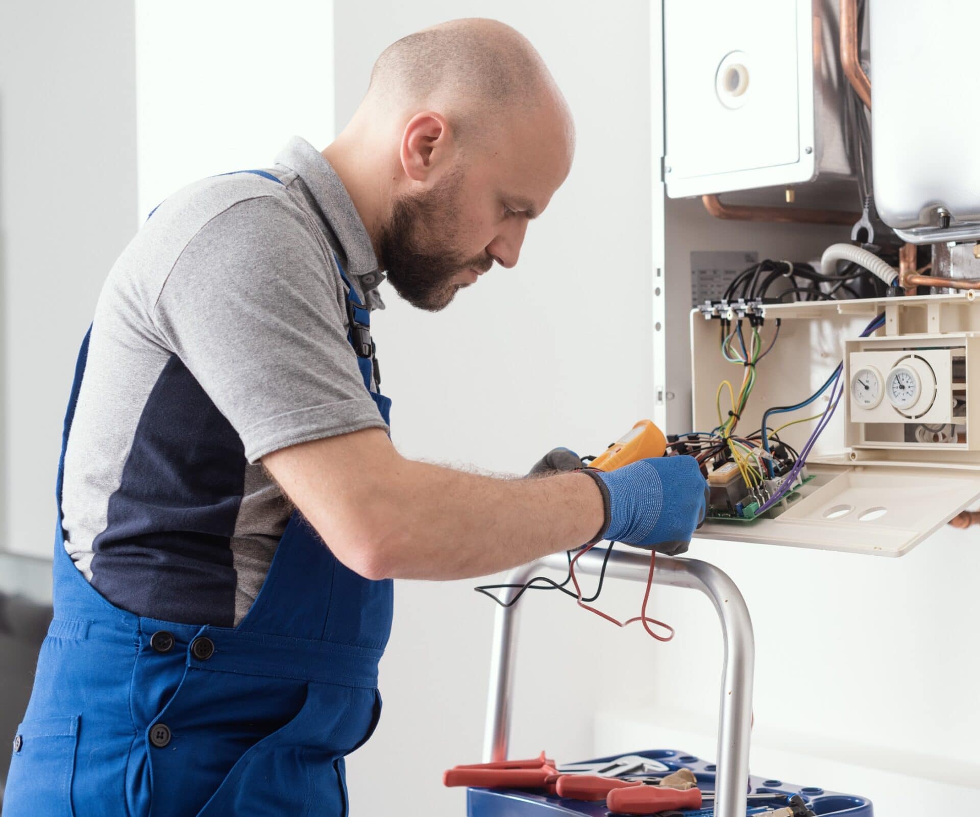 Plumber Servicing Gas Boiler Control Board With Multimeter